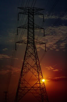 Closeup of high voltage electric pole passing in the countryside with sunset sky photo