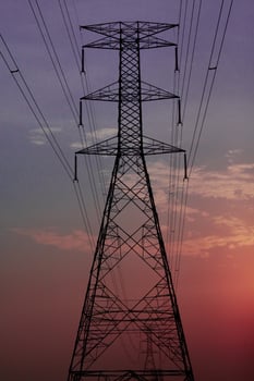 Closeup of high voltage electric pole passing in the countryside with sunset sky photo
