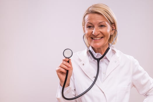 Portrait of mature female doctor with stethoscope on gray background. photo