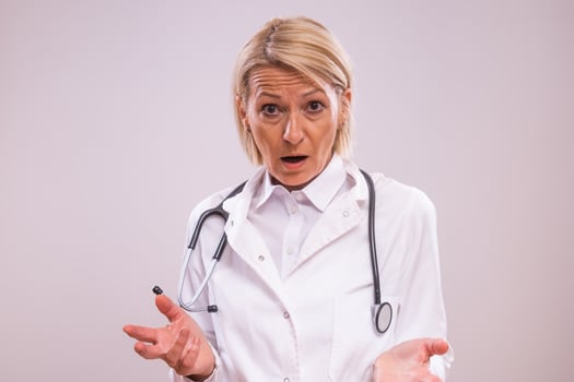 Portrait of shocked mature female doctor on gray background. photo