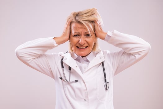Portrait of overworked mature female doctor screaming on gray background. photo