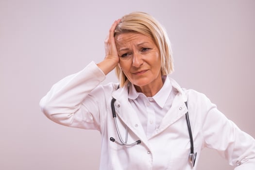 Portrait of tired mature female doctor on gray background photo
