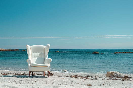 white cozy armchair is sitting on the beach next to the sea photo