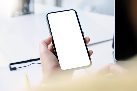 Woman hand holding smartphone on workplace. Blank screen mobile phone for graphic display montage photo