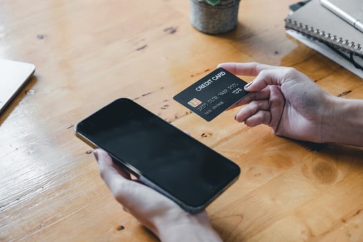 Close up young asian woman holding credit card and using mobile phone. Businesswoman working at home. Online shopping, e-commerce, internet banking, spending money, working from home concept photo