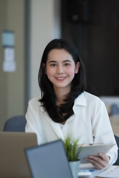Portrait of young beautiful Asian woman looking at camera in office photo