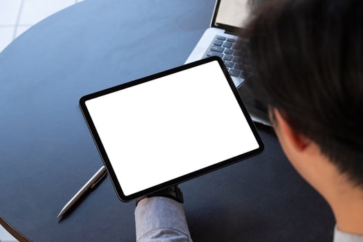 Mockup image of a businessman holding black tablet pc with blank white screen in modern office photo