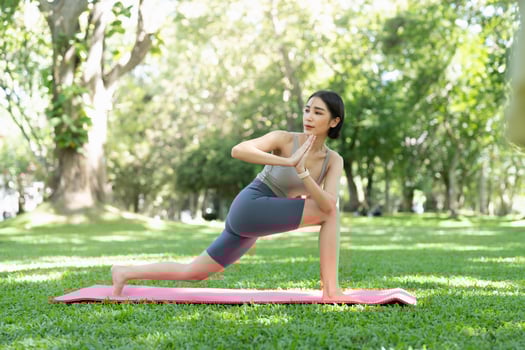 Young attractive girl is doing advanced yoga asana on the fitness mat in the middle of a park. photo