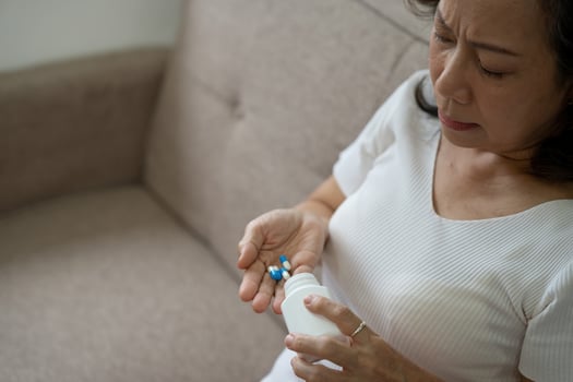 Elderly sick ill woman hold pills on hand pouring capsules from medication bottle take painkiller supplement medicine, old senior people pharmaceutical healthcare treatment concept, close up view photo
