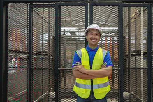 Smiling portrait of a male supervisor standing in warehouse with his arm crossed looking at camera photo