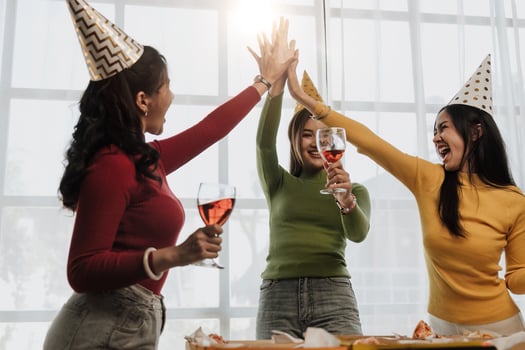 Group of Asian friends gather to celebrate Christmas with champagne and eating pizza at home. Joy of holiday party with friends or colleague concept photo