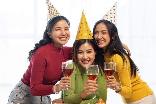 Group of Asian friends gather to celebrate Christmas with champagne and eating pizza at home. Joy of holiday party with friends or colleague concept photo