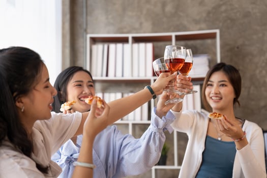 Group of Asian friends gather to celebrate Christmas with champagne and eating pizza at home. Joy of holiday party with friends or colleague concept photo