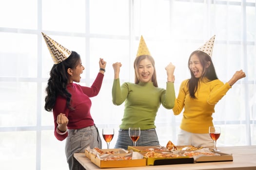 Group of Asian friends gather to celebrate Christmas with champagne and eating pizza at home. Joy of holiday party with friends or colleague concept photo