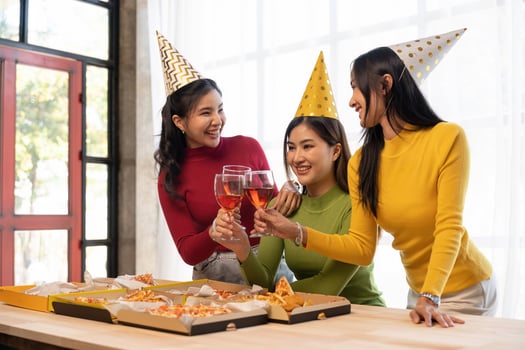 Group of Asian friends gather to celebrate Christmas with champagne and eating pizza at home. Joy of holiday party with friends or colleague concept photo