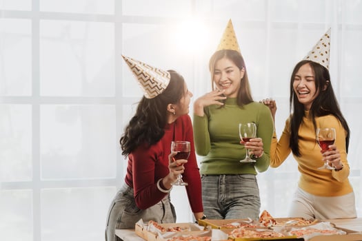 Group of Asian friends gather to celebrate Christmas with champagne and eating pizza at home. Joy of holiday party with friends or colleague concept photo