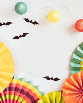Helloween composition with colorful paper fans, helloween decorations and light garland on a blue background photo