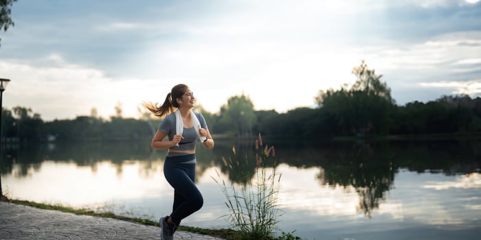 Jogging woman running in park on beautiful day off. Sport fitness model of asian ethnicity training outdoor for marathon photo