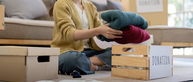 Donation, asian young woman sitting pack object at home, putting on stuff into donate box with second hand clothes, charity helping and needy people. Reuse recycle photo