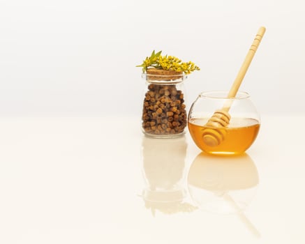 Bee products in glass jars on a white table with copy space photo