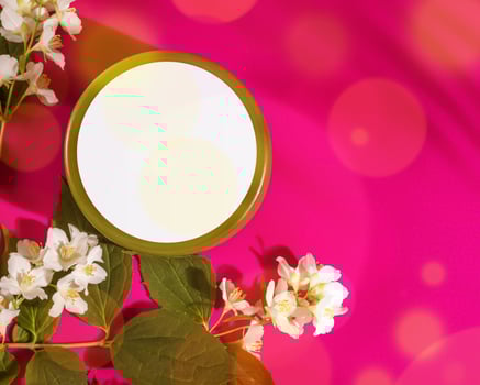 Natural cosmetic product in a round jar and jasmin flowers on a pink background photo