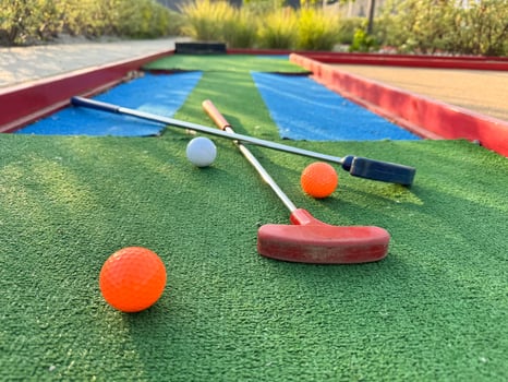 colorful golf putters with golf balls on synthetic grass photo