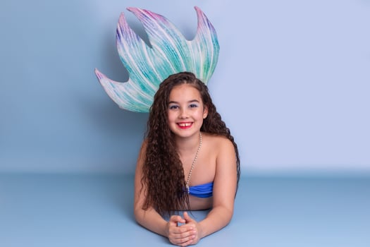 Beautiful girl in a mermaid costume lie on light-blue background photo