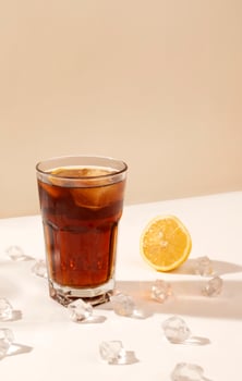 glass of alcoholic drink on the table with ice cubes and lemon. long shadow. party and cocktail concept. rum and cola photo