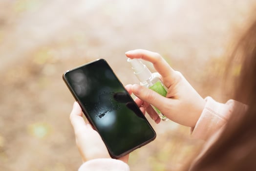 How to clean, sanitize your phone. Cleaning mobile phone to eliminate germs, coronavirus Covid-19. Man hands cleaning smartphone by alcohol hand sanitizer and wipe with cloth. photo