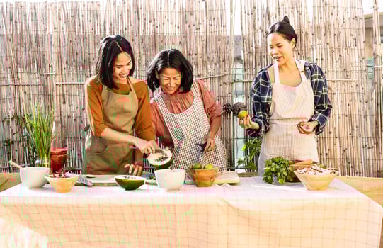 Happy Southeast Asian mother and daughters are having fun cooking a Thai food recipe together in the backyard photo