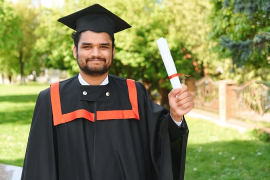 Handsome indian graduate in graduation glow with diploma photo