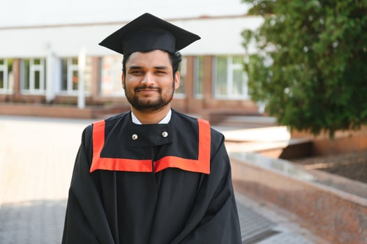 Handsome indian graduate in graduation glow with diploma photo