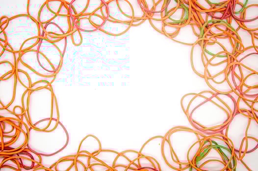 a collection of rubber bands that form a frame with white copy space in the middle photo
