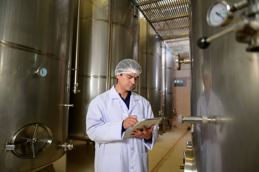 Professional winemaker controlling wine making process and quality at winery factory photo