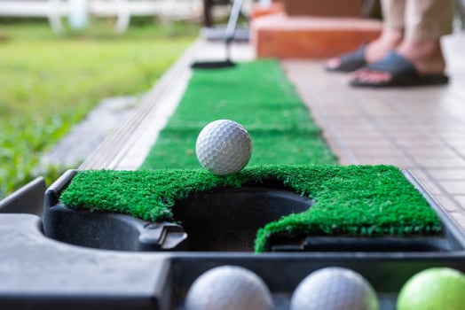 Golfer putting a golf ball into the edge hole photo