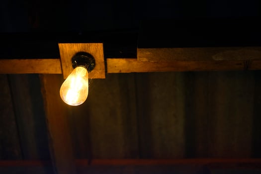 Light bulbs is hanging on wooden beam indoor of cafe and vintage house building photo