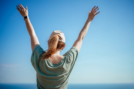 Woman tourist sky sea. Happy traveler woman in hat enjoys vacation raised her hands up photo