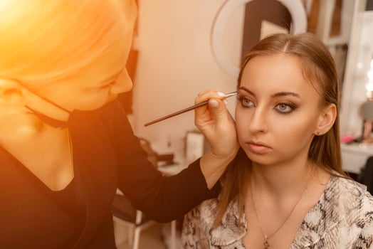Make-up artist paints eyebrow pencil to beautiful brunette in be photo