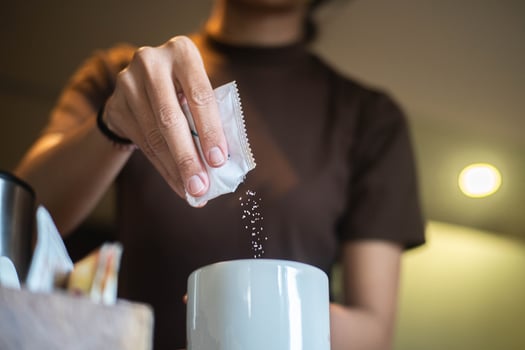 Person pouring sugar into a mug photo