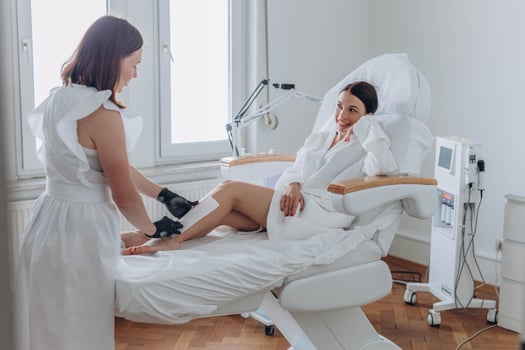 Beautician depilating young woman's legs with liquid sugar in spa center photo