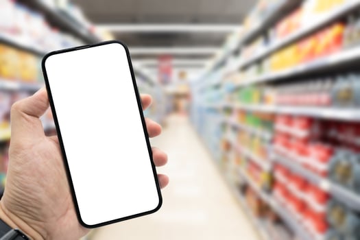 Hand holding blank screen smartphone for copy space on blurred Miscellaneous Product shelf. e-commerce app shopping mockup. social media, payment and shopping online concept. photo