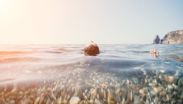 Woman swimming in sea at sunset, float on calm water back view. Concept of body image and fitness, enjoying a serene beach. Happy woman with perfect fit body enjoys sea beach photo