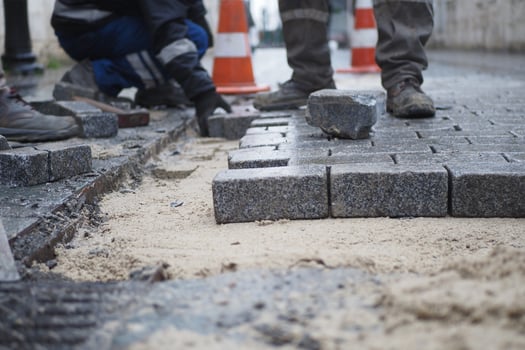 a worker laying concrete bricks on each other for building a new sidewalk photo