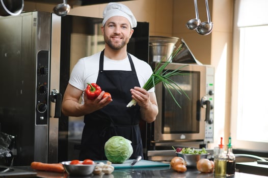 Portrait of happy caucasian male chef standing in restaurant kitchen, copy space photo