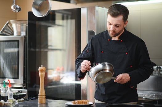 Closeup of a concentrated male chef garnishing food in the kitchen photo