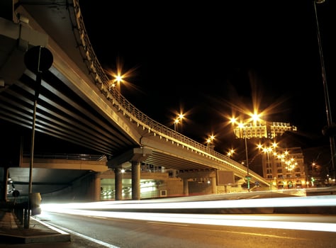 Car lights traces under road bridge with city lights at the night street photo