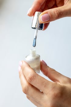 Shot of the beautiful woman's hand holding bottle of nail enamel. Fashion photo