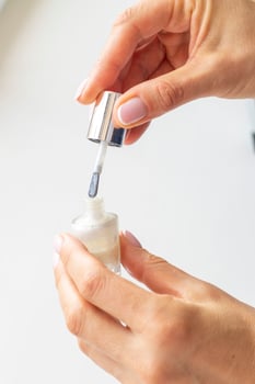 Shot of the beautiful woman's hand holding bottle of nail enamel. Fashion photo