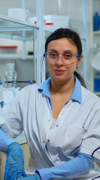 Tired laboratory doctor looking at camera smiling in modern equipped lab. Multiethnic team examining virus evolution using high tech and chemistry tools for scientific research, vaccine development. photo