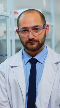 Portrait of exhausted chemist looking at camera in modern equipped lab. Multiethnic team examining virus evolution using high tech and chemistry tools for scientific research, vaccine development. photo